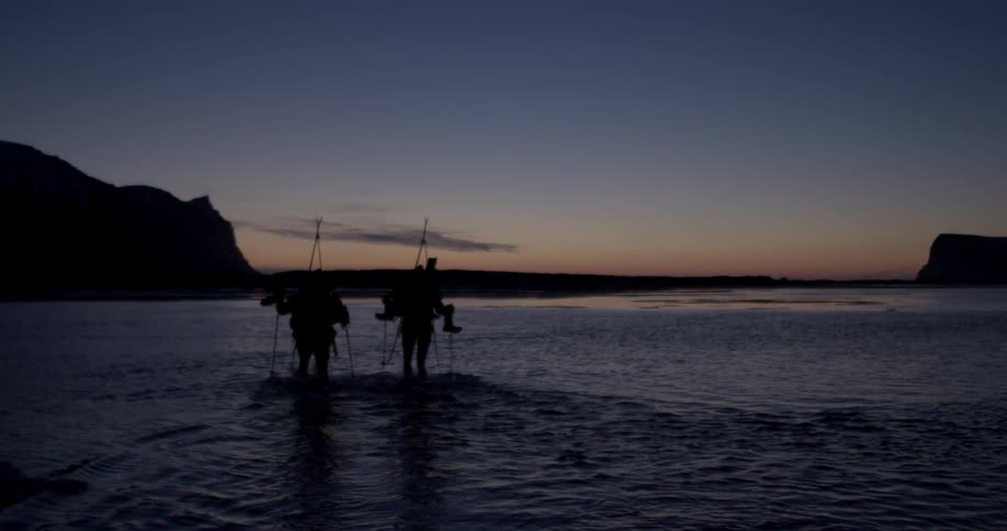 The two fisherman walk into the sea at sunset