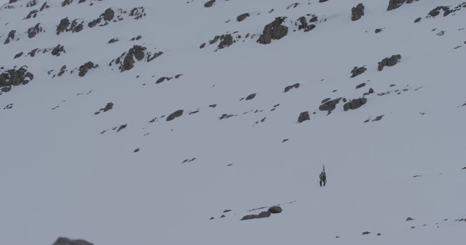 Man walking across a snowy slope in the wilderness