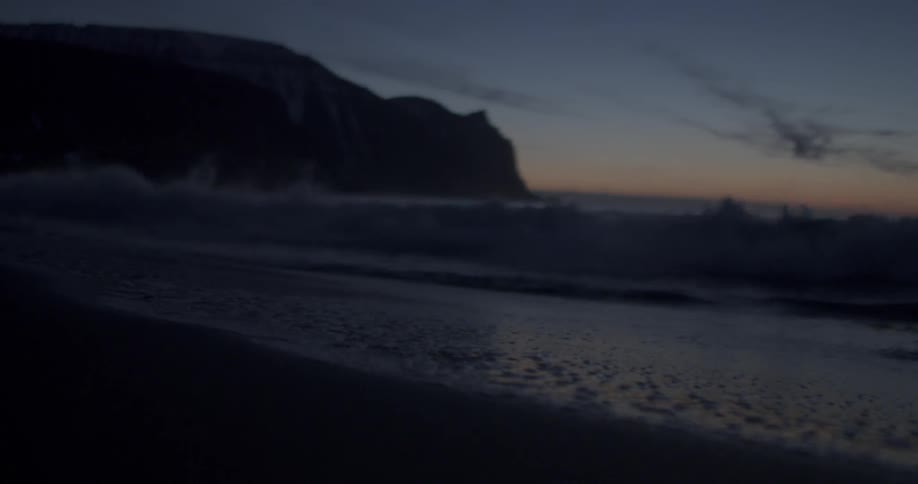 The waves crash against the shore at dawn