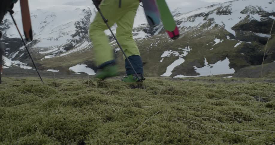 Hikers carrying skis are walking in a mountain landscape during the day