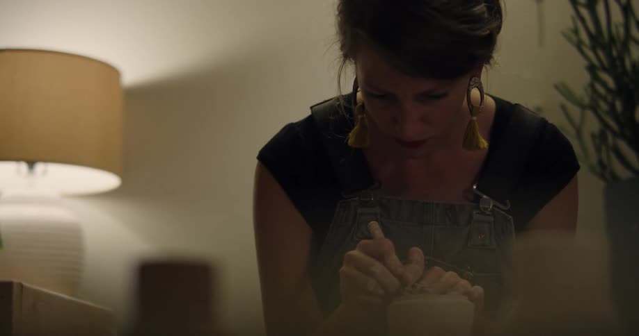 A woman is carving a clay pot
