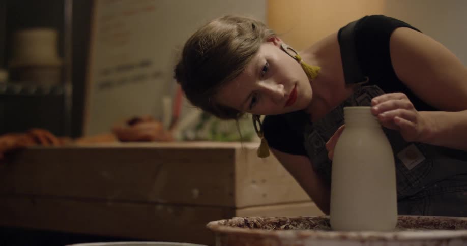 A woman is using a pottery wheel to make a vase