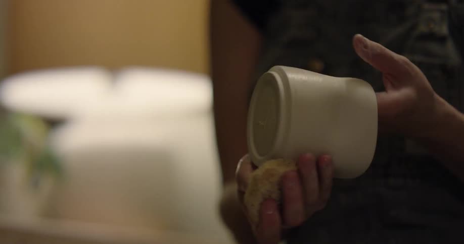A woman is wiping down a piece of pottery she has made