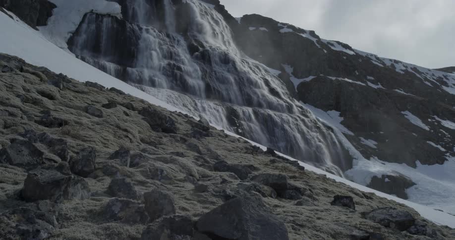 Majestic waterfall emits mist with a rocky moss foreground