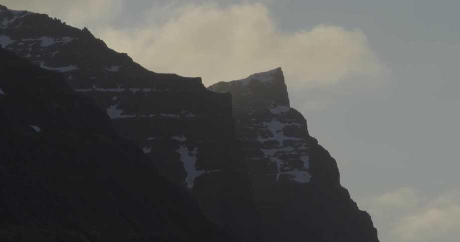 The clouds move past the tall mountain