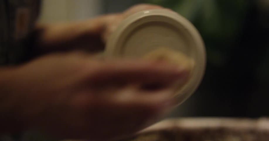 A person wiping down a pottery cup they just made