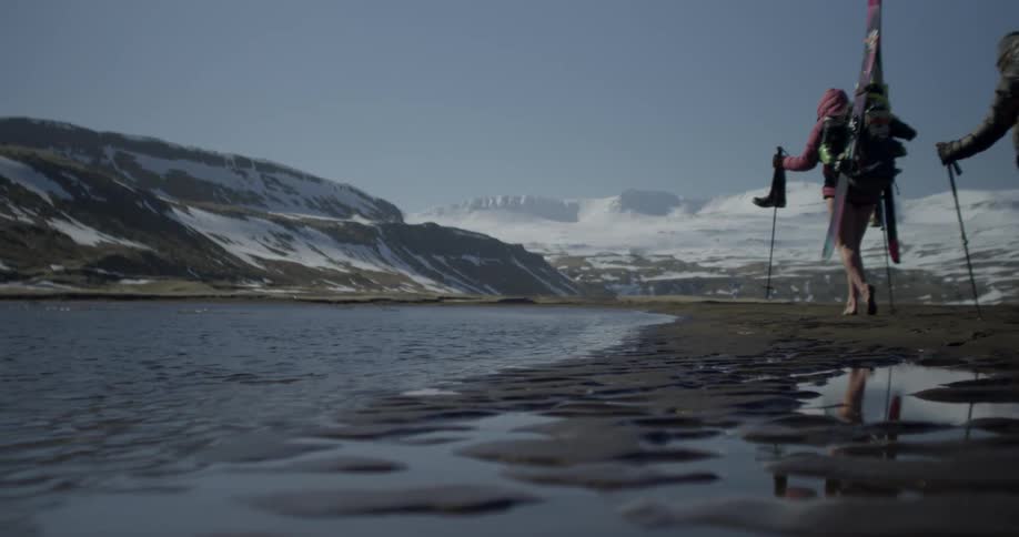 Skiers hike by a mountain lake