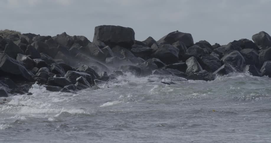 Waves are crashing onto a jetty during the day