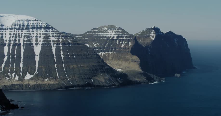 Snow covered mountains are surrounded by the ocean
