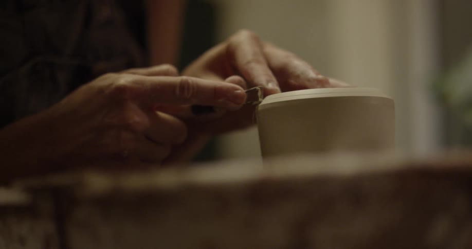A potter shaves a piece of clay