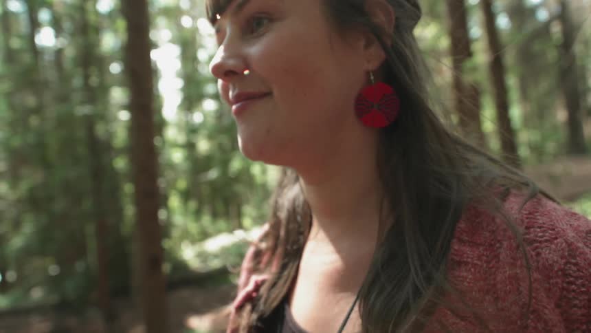 A woman is smiling as she walks through the woods