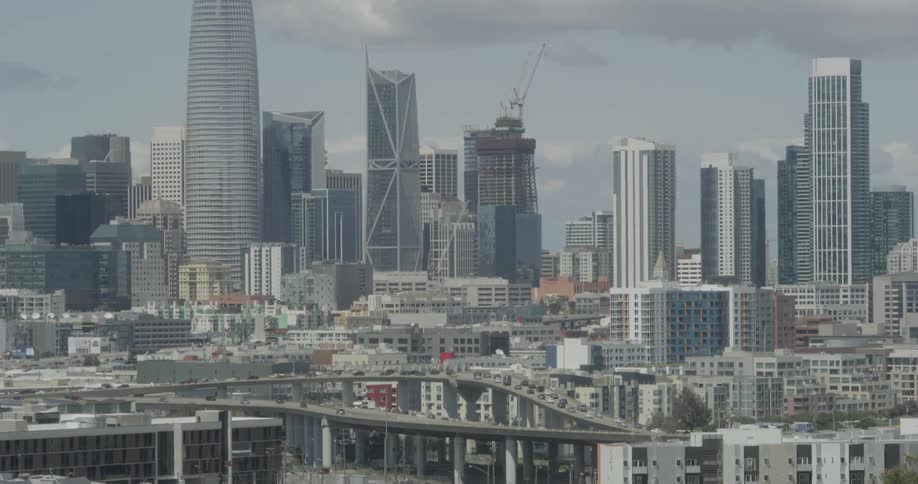 The cars are traveling over the bridge towards the city