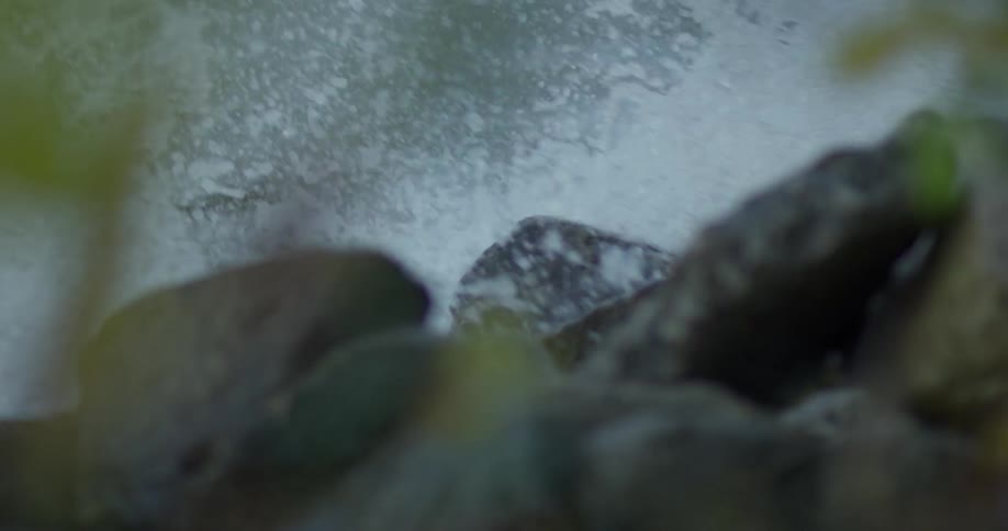 Waves are crashing over rocks during the day