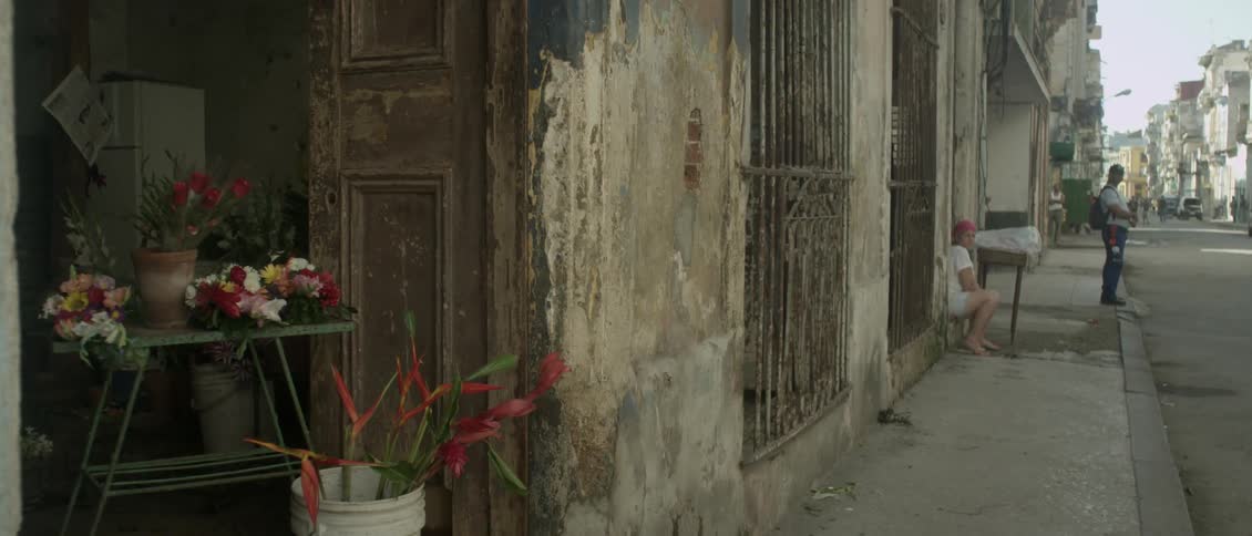A woman is sitting on a ledge on a city sidewalk during the day