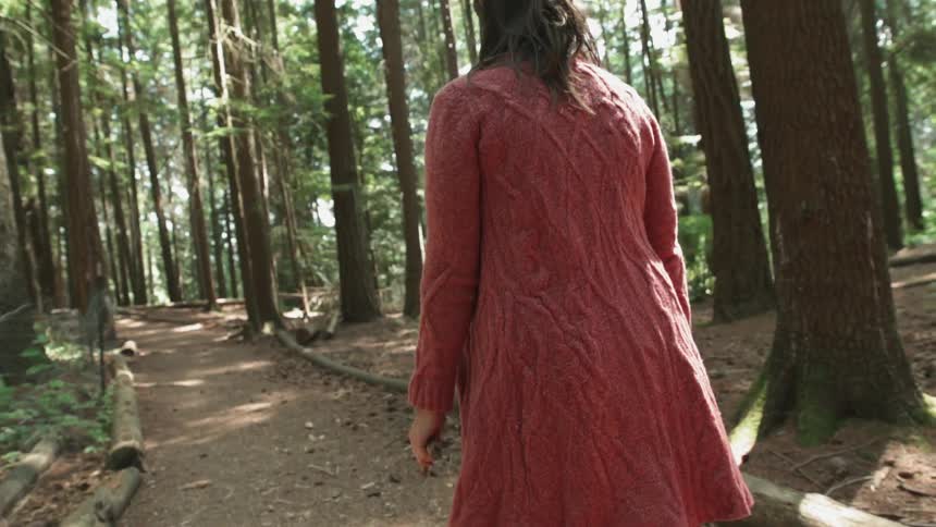 A woman is hiking down a trail in the forest