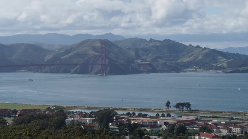 Boats are sailing on the bay beneath the golden gate bridge