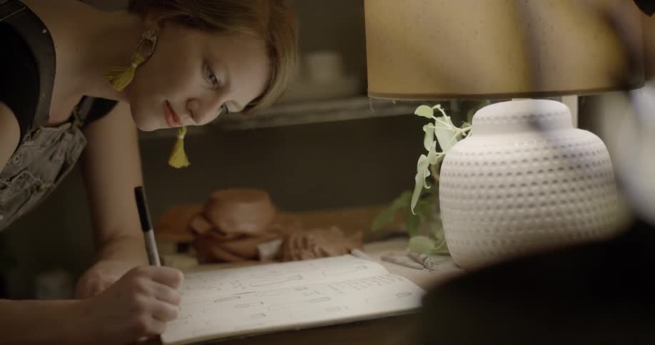 A woman is writing something down in a book with a marker