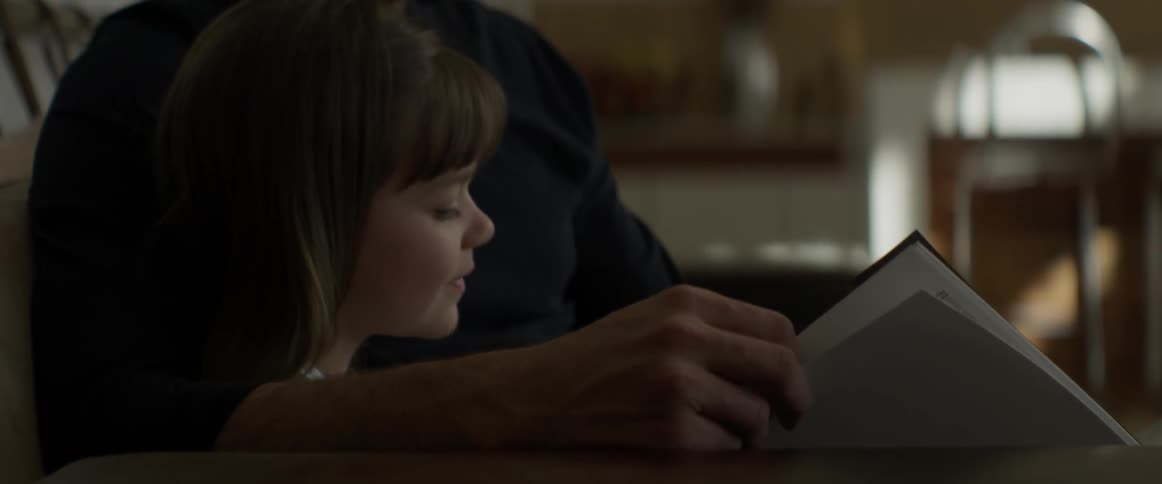Man reading to a child as they sit indoors