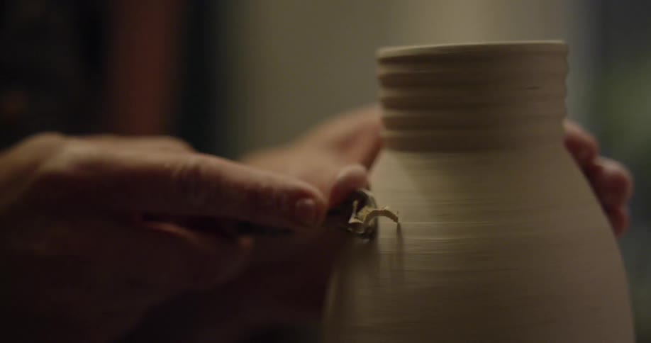 An artisan is working on a clay vase on a pottery wheel