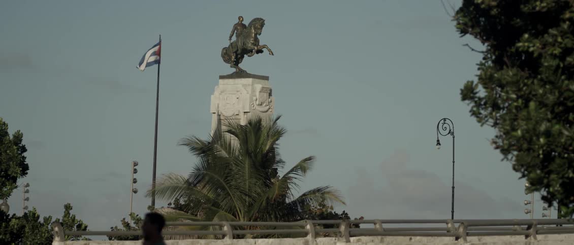 A flag billows next to a statue
