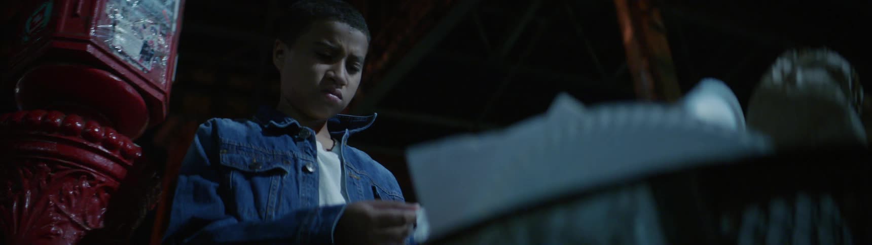 A boy looking down frowning before digging in the trash