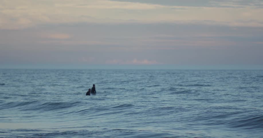 People sitting in the ocean at sunset