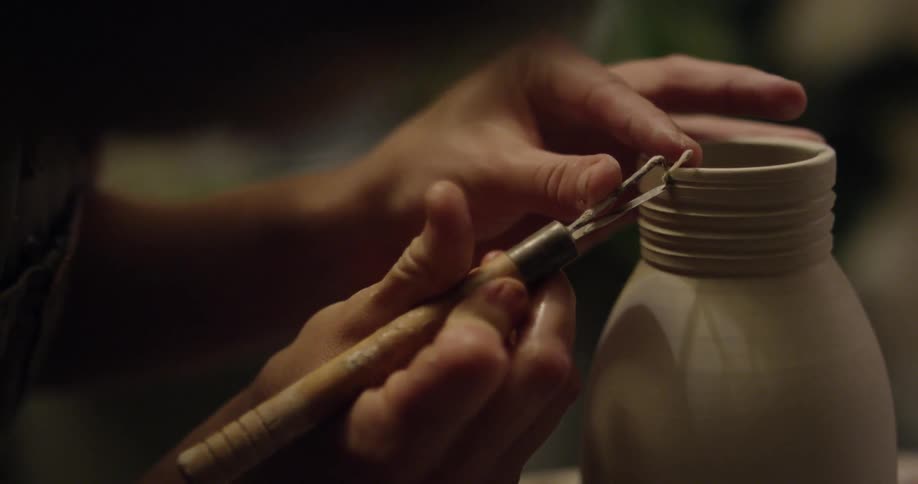 A woman is crafting a piece of pottery on a wheel