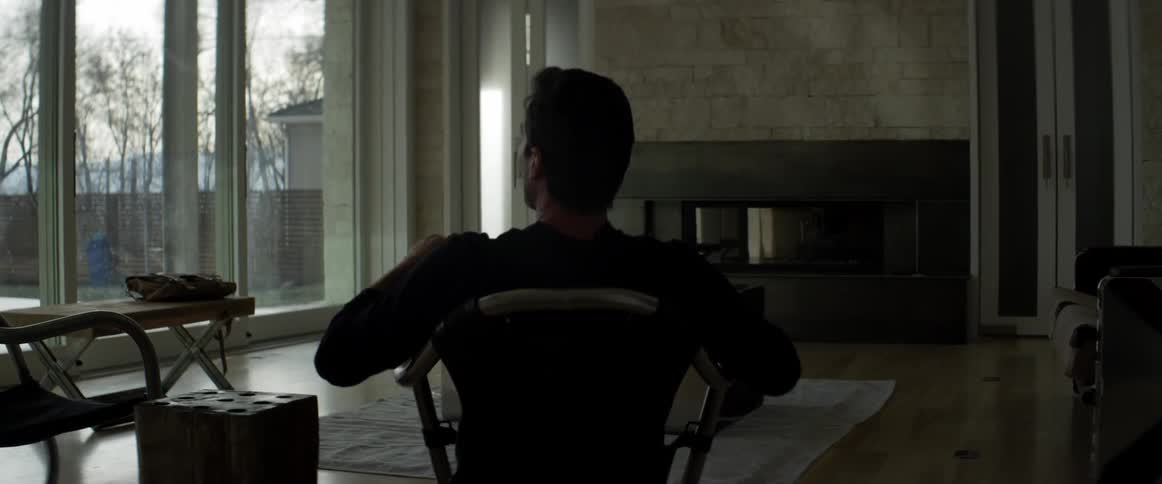 A man with a book sits in a chair