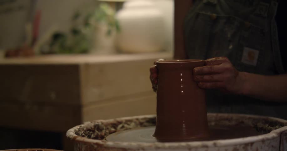 A woman making pottery inside her home at the table
