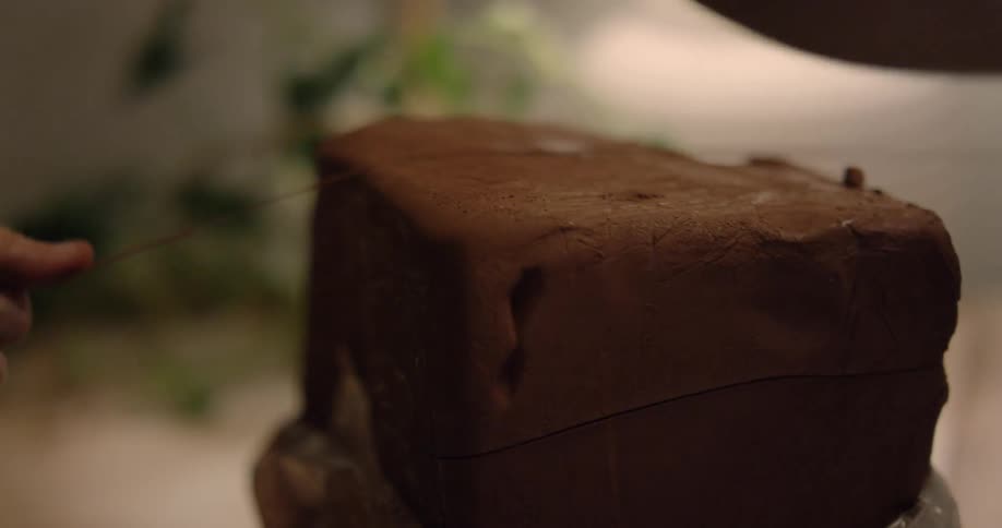 A person slices clay with a wire
