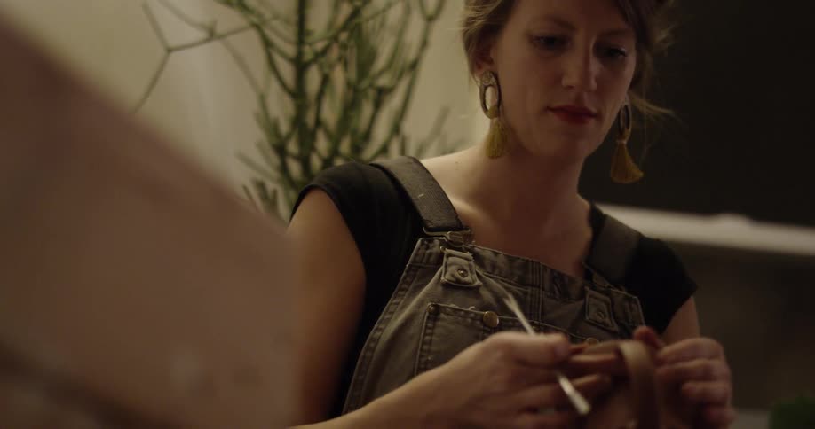 A woman making pottery inside her home at the table