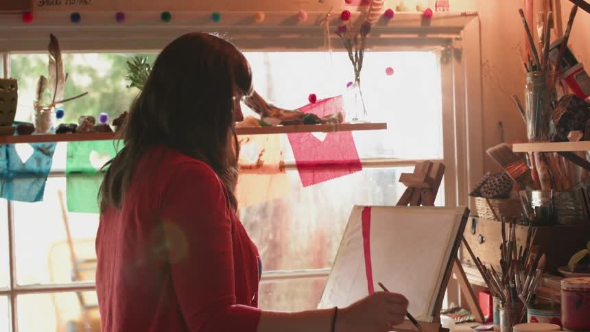 Woman artist painting on her medium indoors