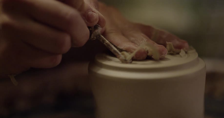 A person is creating a mug with pottery