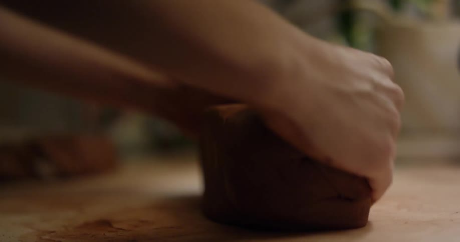 A woman is rolling out a large clay ball