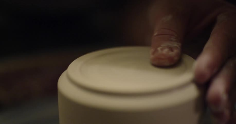 A person is making a mug with pottery and a sponge