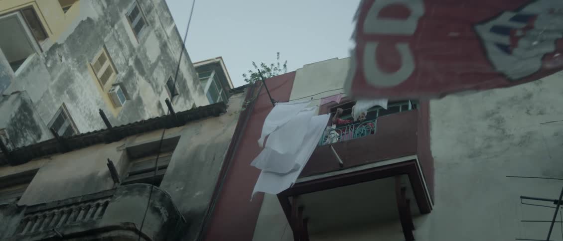 An old woman is checking laundry hung outside her balcony on windy day