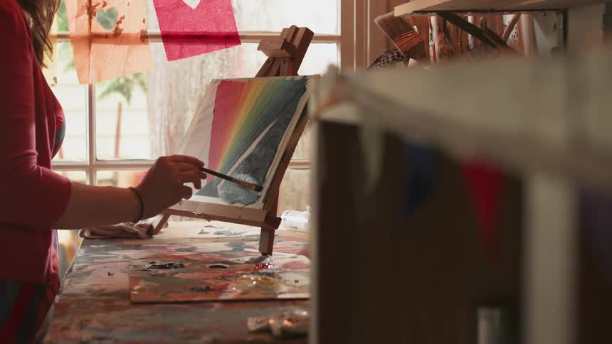 A woman is painting on a small canvas