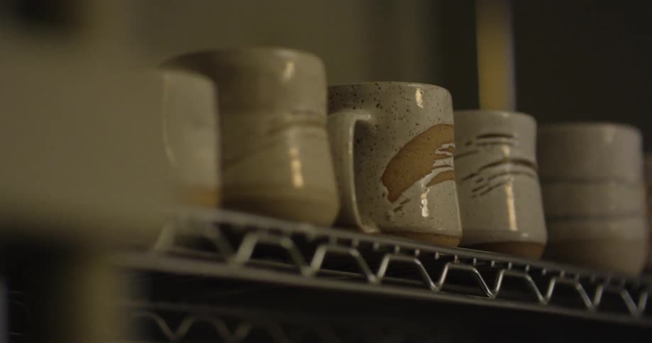 A shelf is holding pottery mugs