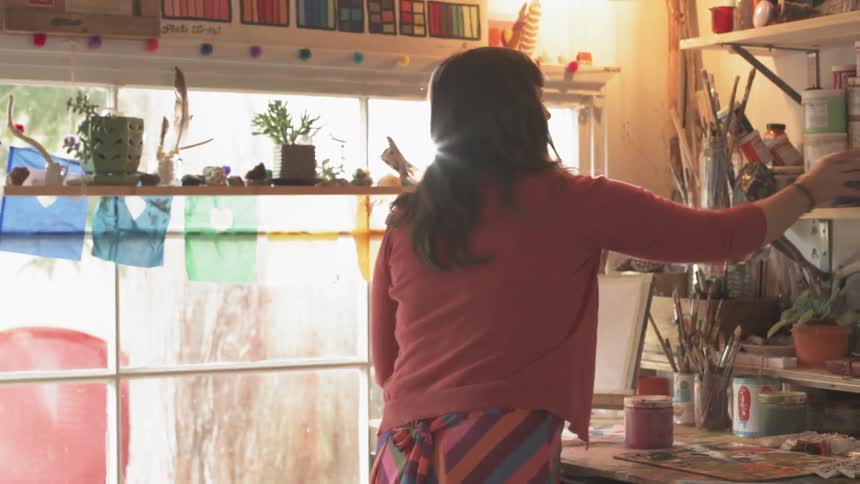 A woman pulls paint from a shelf
