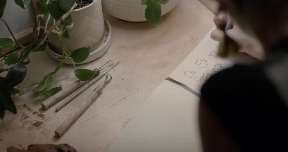 A person drawing on a piece of paper with a pen