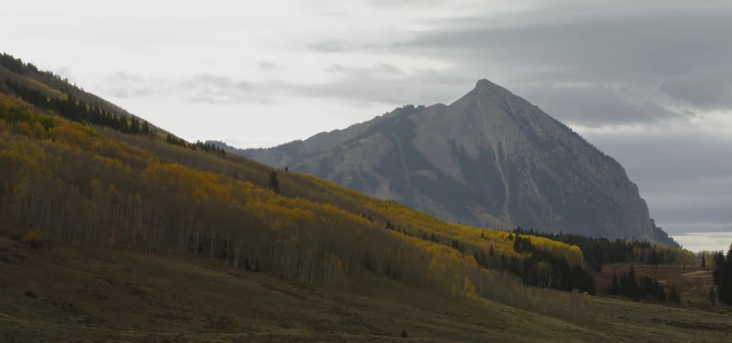 Fall foliage covers a mountainside on a cloudy day