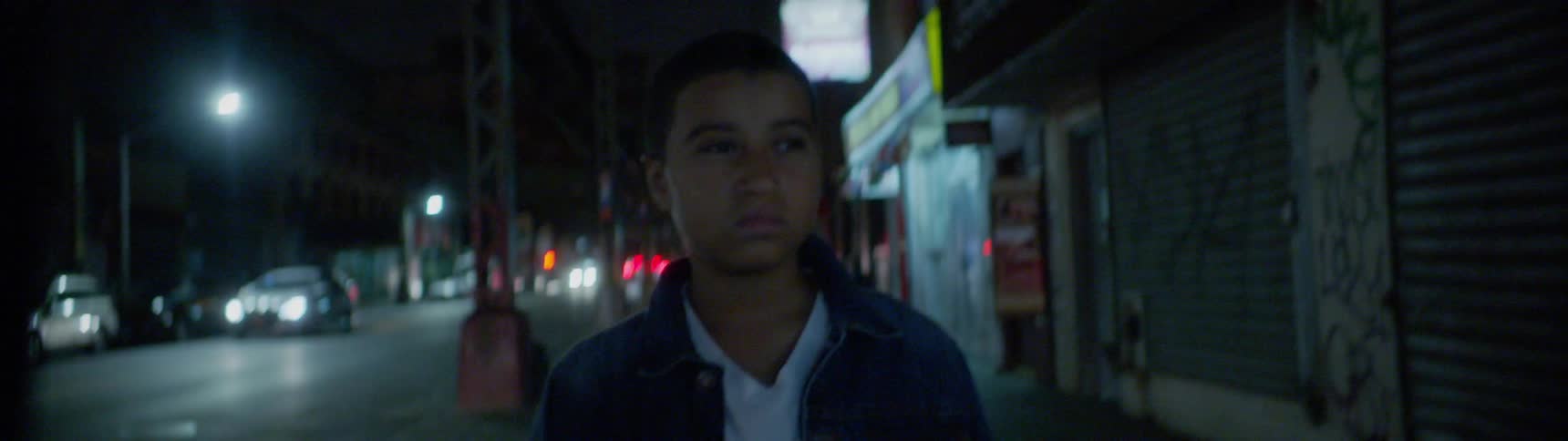 A boy walks through the city at night