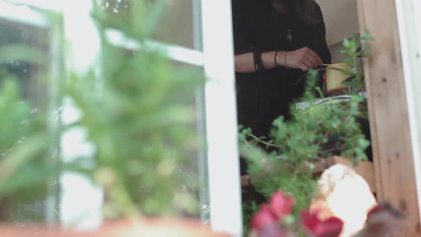 A woman is using a stick to get something out of a jar and onto something