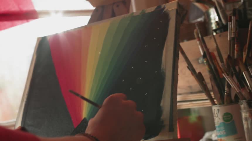 An artist paints on a canvas in an art studio during the day
