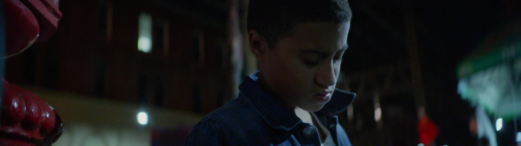 A young boy is looking in the garbage can for food