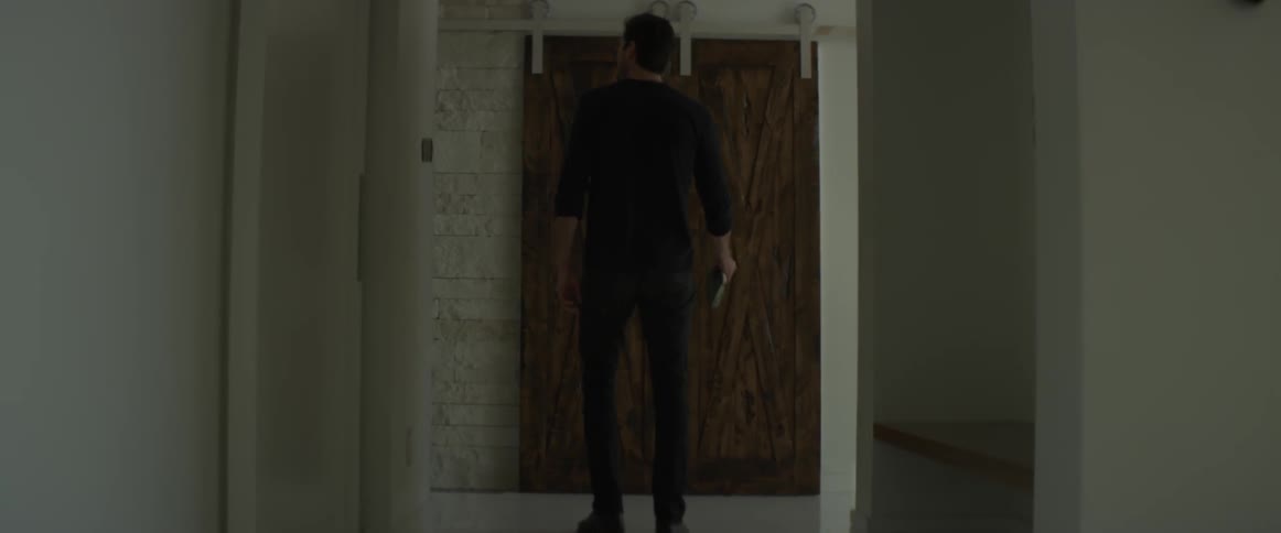 A man is walking down a hallway and turning left during the day