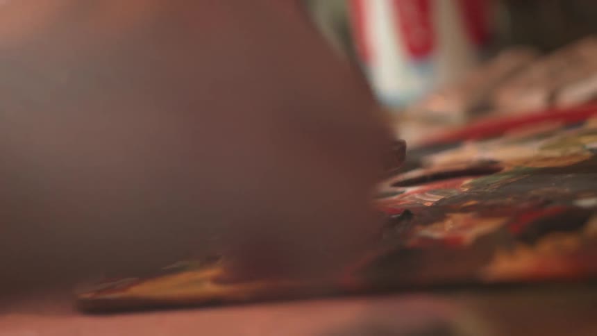 An artist mixes paint on a palette