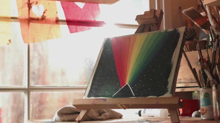 A view of a painting on top of a counter that is black and rainbow colored