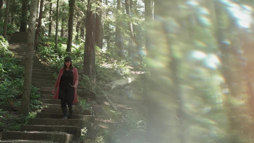 A woman walks down steps in the woods
