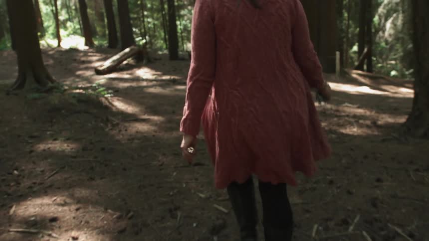 A woman walks alone in a forest
